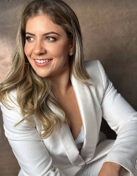Erica Hartmann sorrindo, de terno branco